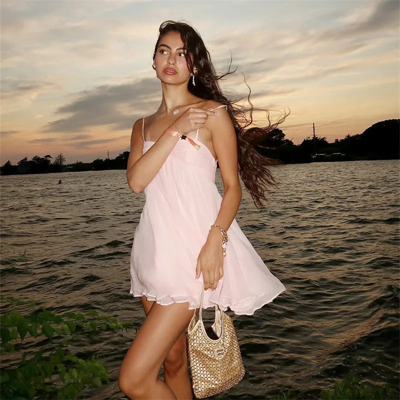 Robe Maéva rose courte avec dos nu et sac tissé en bord de l’eau