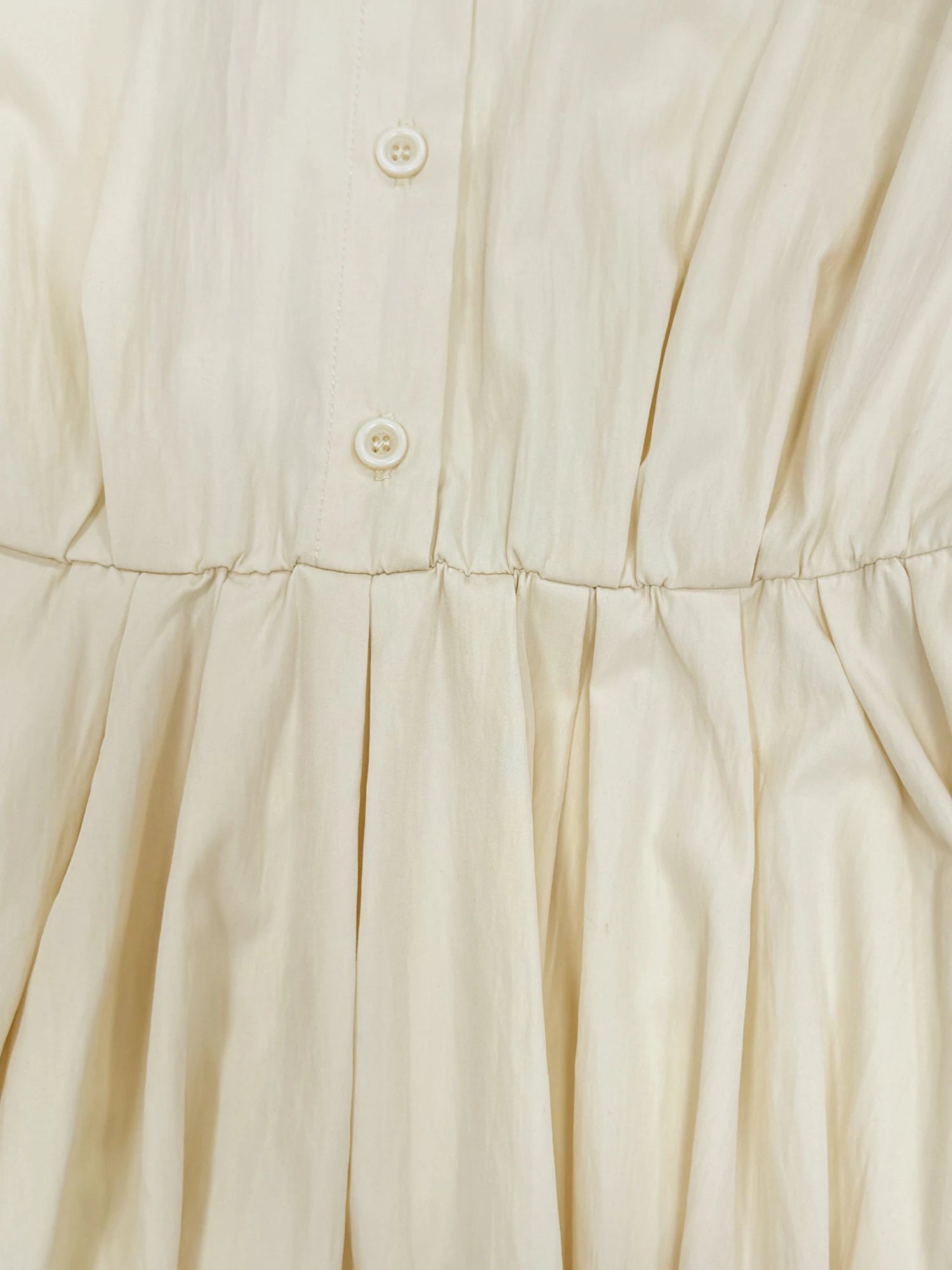 Détail du boutonnage et de la taille de la robe chemise écrue