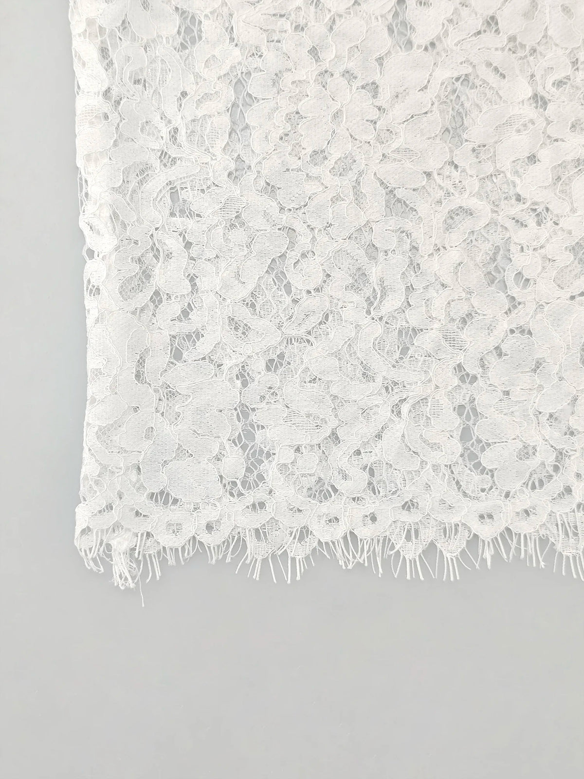 Détail du bord festonné du chemisier blanc en dentelle