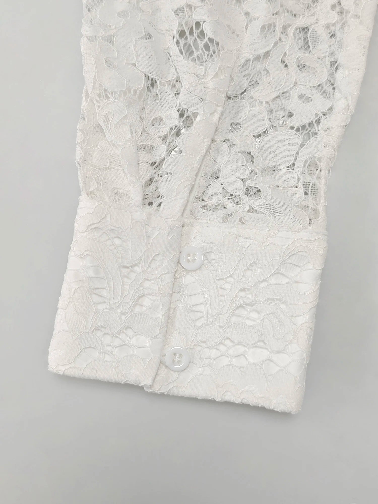 Détail du poignet boutonné du chemisier blanc en dentelle